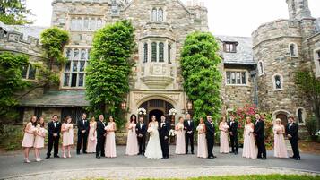 A group of people in front of a historic stone building with arched windows and a central entrance.