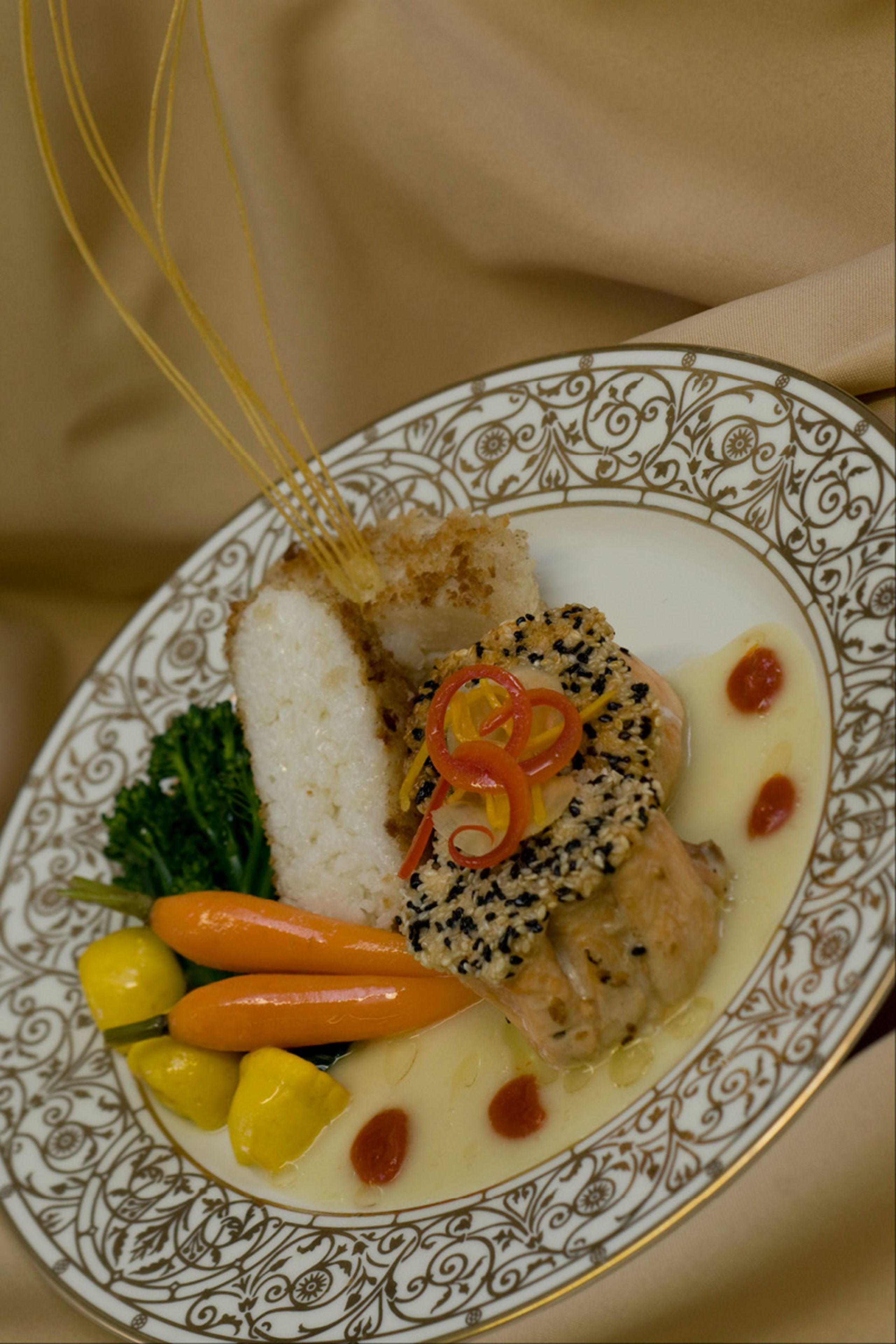 A plate of food with a fish fillet, vegetables, and a sauce.