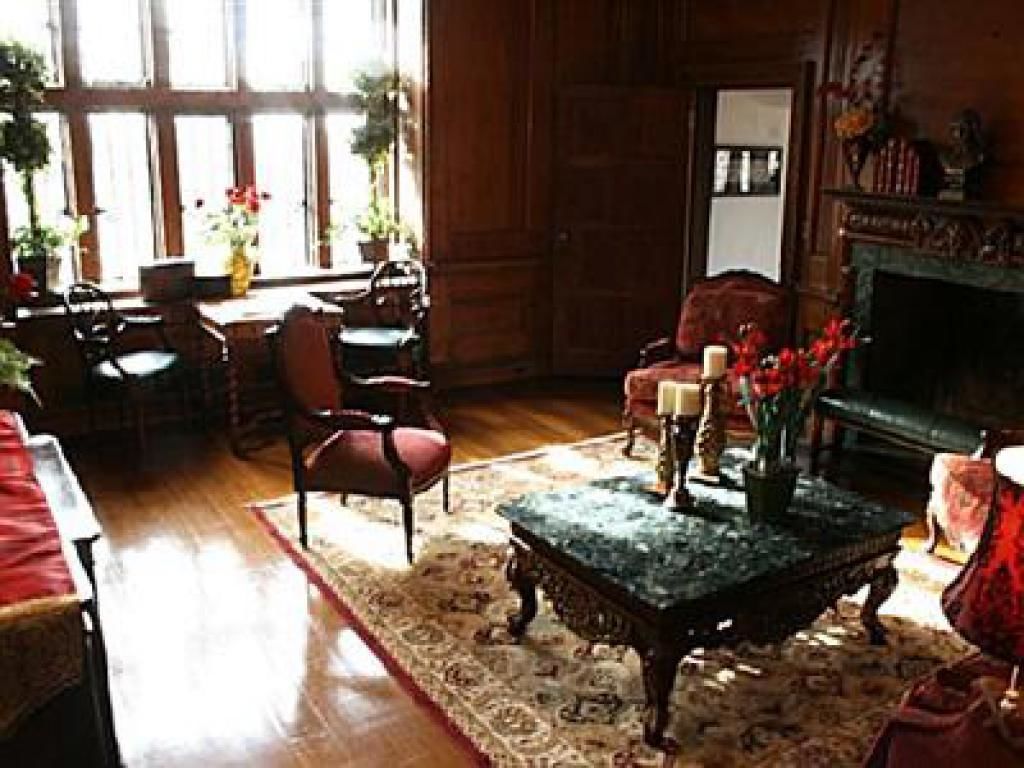 A traditional room with wooden paneled walls, a fireplace, and a large window with curtains.