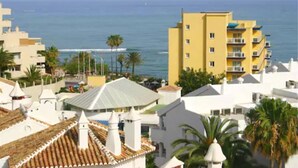Un hôtel situé sur la côte, avec des bâtiments blancs, un bâtiment jaune doté de balcons et une vue sur la mer.
