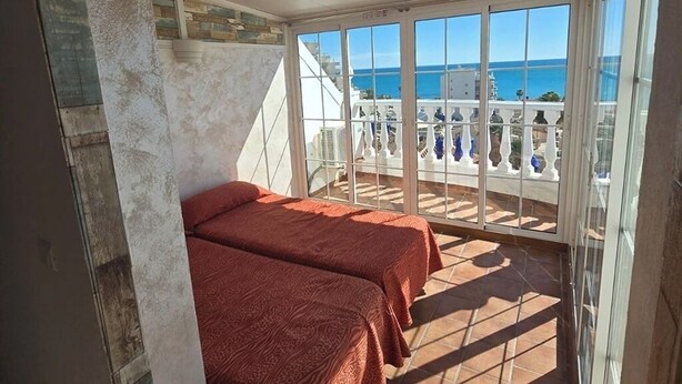 Un balcon avec deux lits, une vue sur la mer et une balustrade blanche.