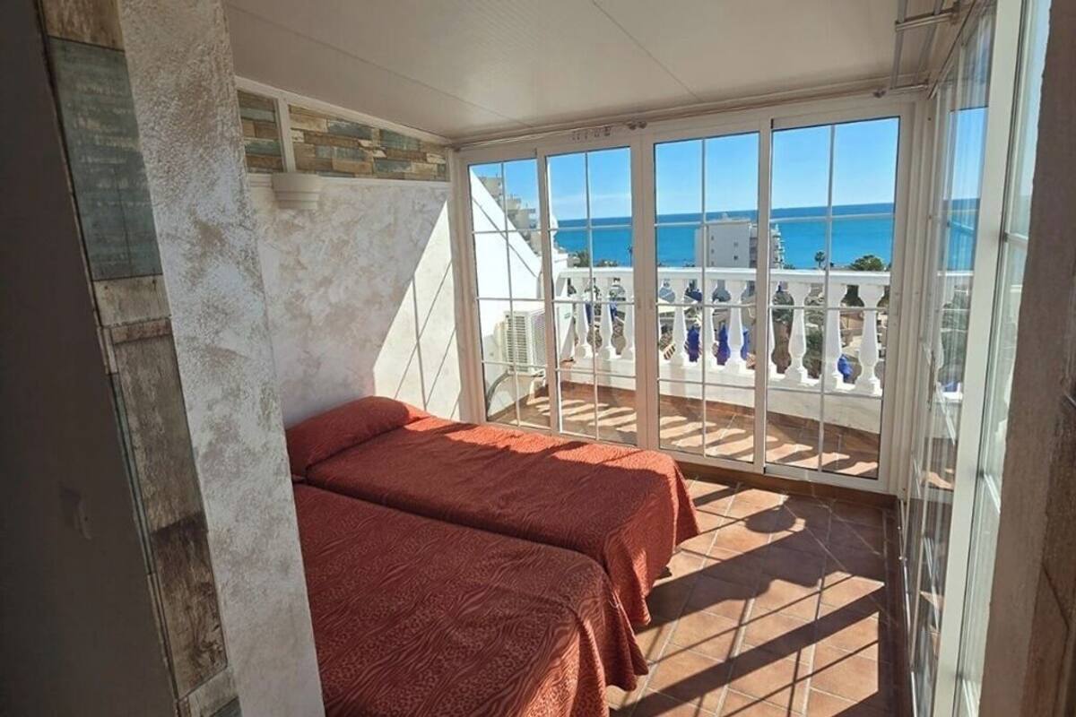 Un balcon avec deux lits, une vue sur la mer et une balustrade blanche.