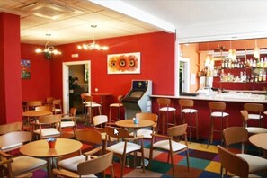 Een restaurant met rode wanden, meerdere tafels en stoelen, een bar met flessen en een plafond met verlichting.