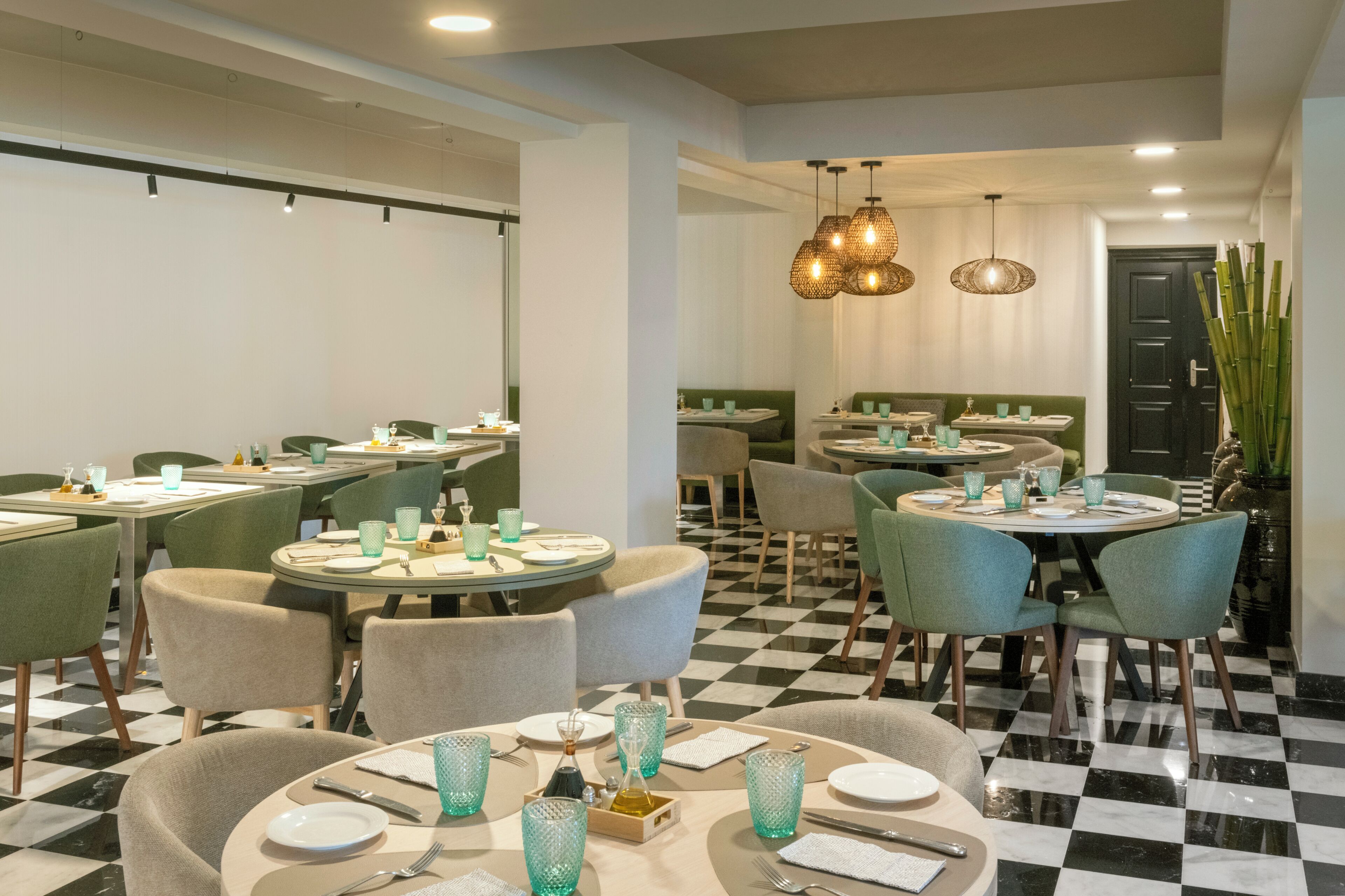 Un restaurant amb taules rodones, cadires i un paviment a escacs.