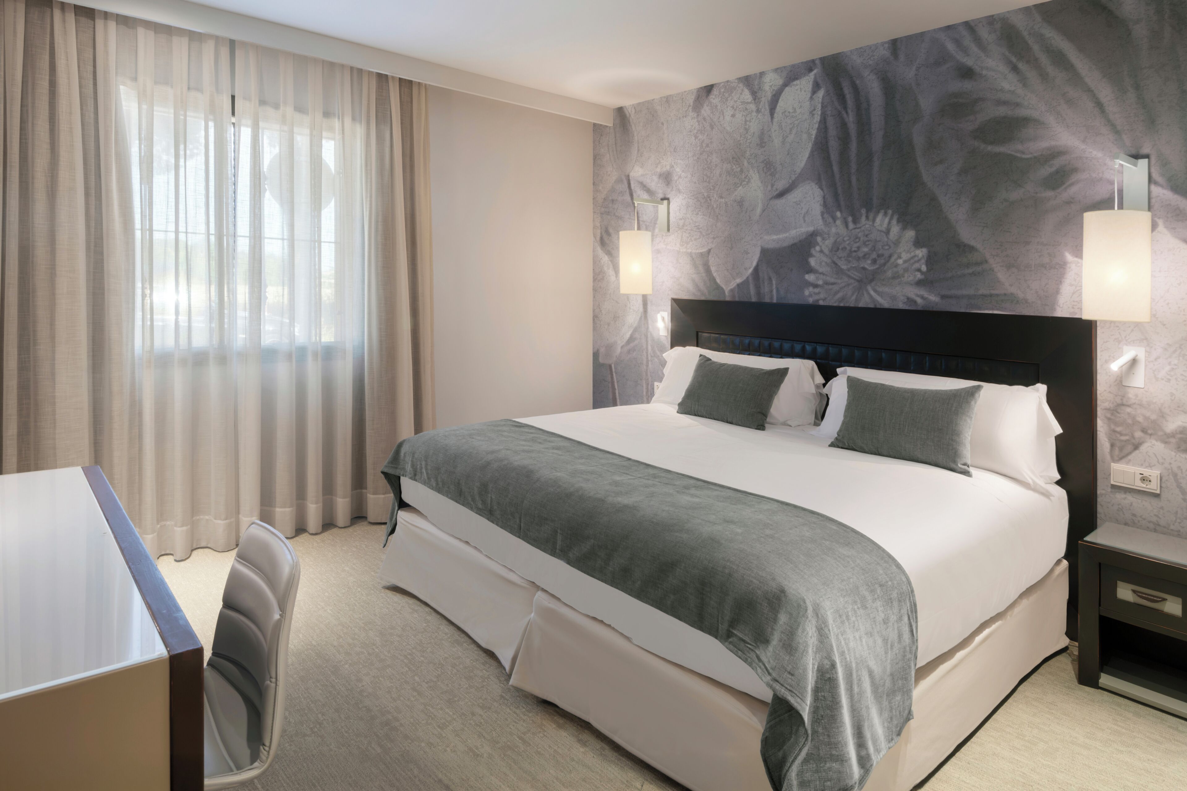Une chambre d’hôtel avec un grand lit, un bureau et une chaise.