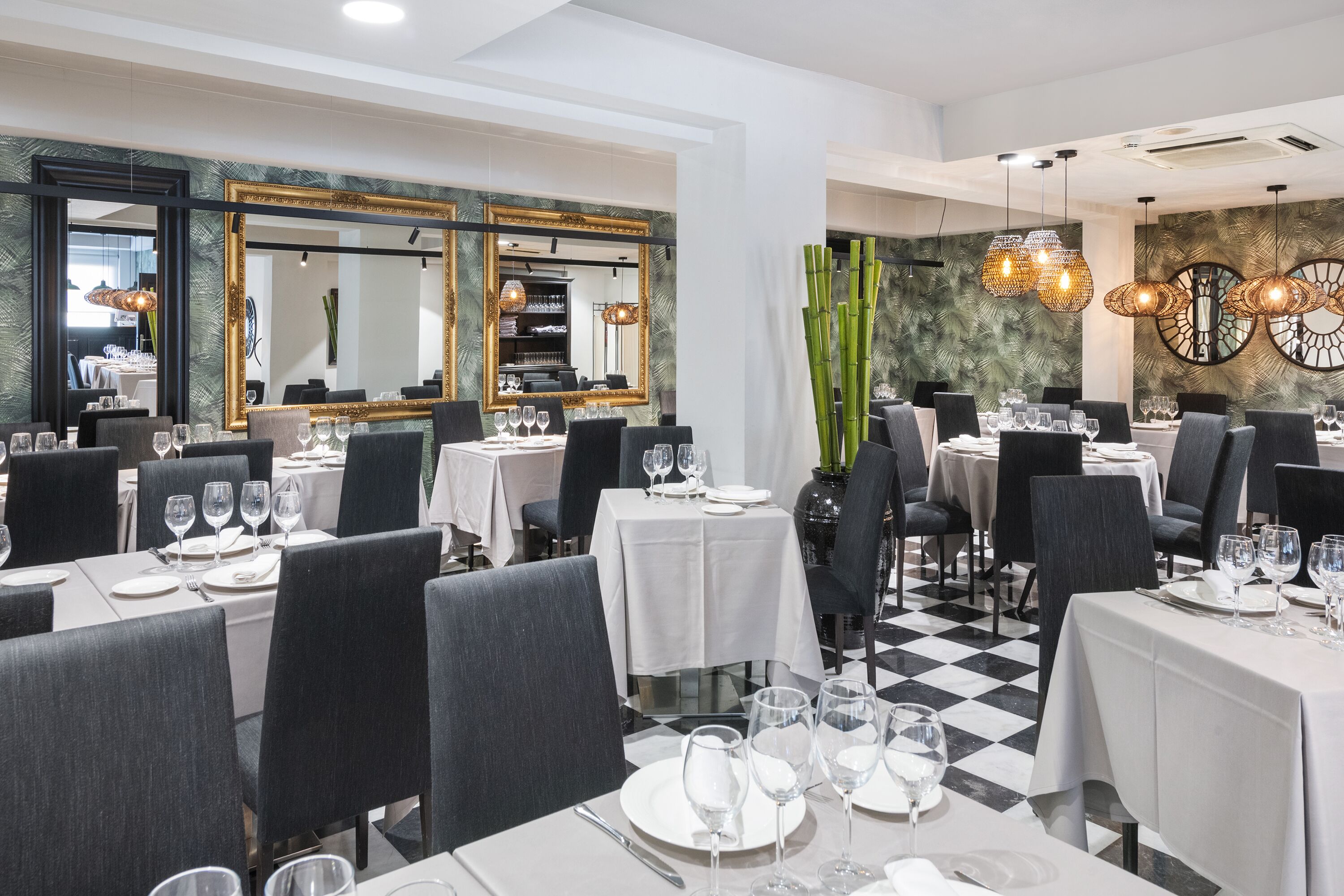A restaurant with multiple tables set for dining, featuring a checkered floor and modern decor.