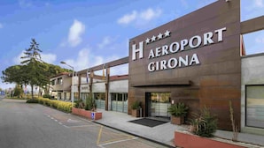 A modern building with a sign reading "H AEROPORT GIRONA". - Salles Hotel Aeroport de Girona (Riudellots de la Selva)