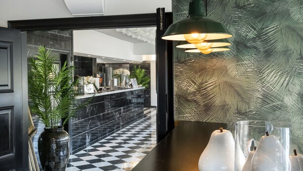 A lobby with a checkered floor, a reception desk, and a large potted plant. - Salles Hotel Aeroport de Girona (Riudellots de la Selva)