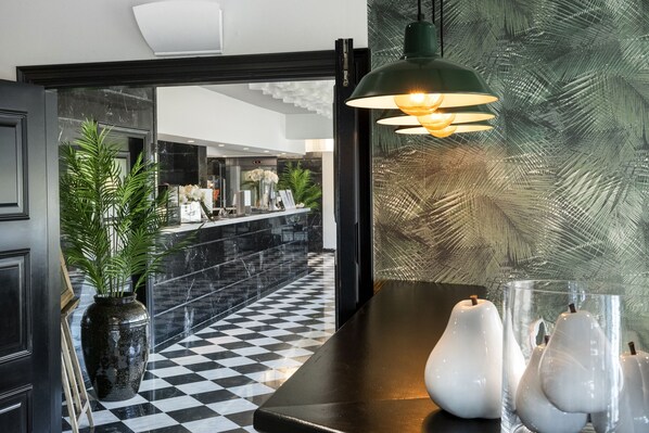 A lobby with a checkered floor, a reception desk, and a large potted plant. - Salles Hotel Aeroport de Girona (Riudellots de la Selva)