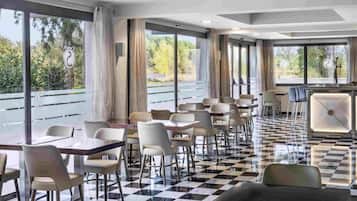 A modern restaurant with a checkered floor, large windows, and a bar area.