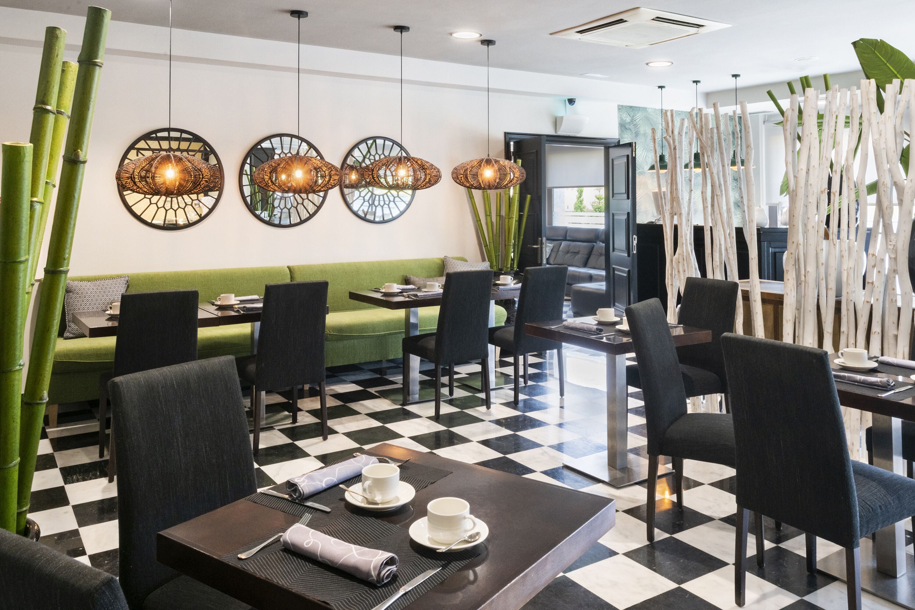 En moderne restaurant med skakternet gulv, bambusindretning og tidssvarende lysarmaturer.