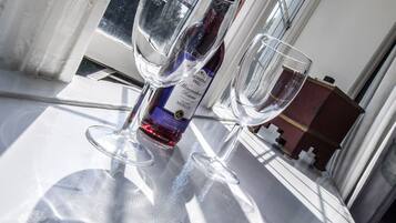 A table with two wine glasses and a bottle of wine, positioned near a window with a view of trees.
