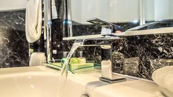 A modern bathroom with a marble sink, a glass soap dish, and a towel hanging on the wall.