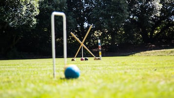 A croquet set on a grassy field with trees in the background.