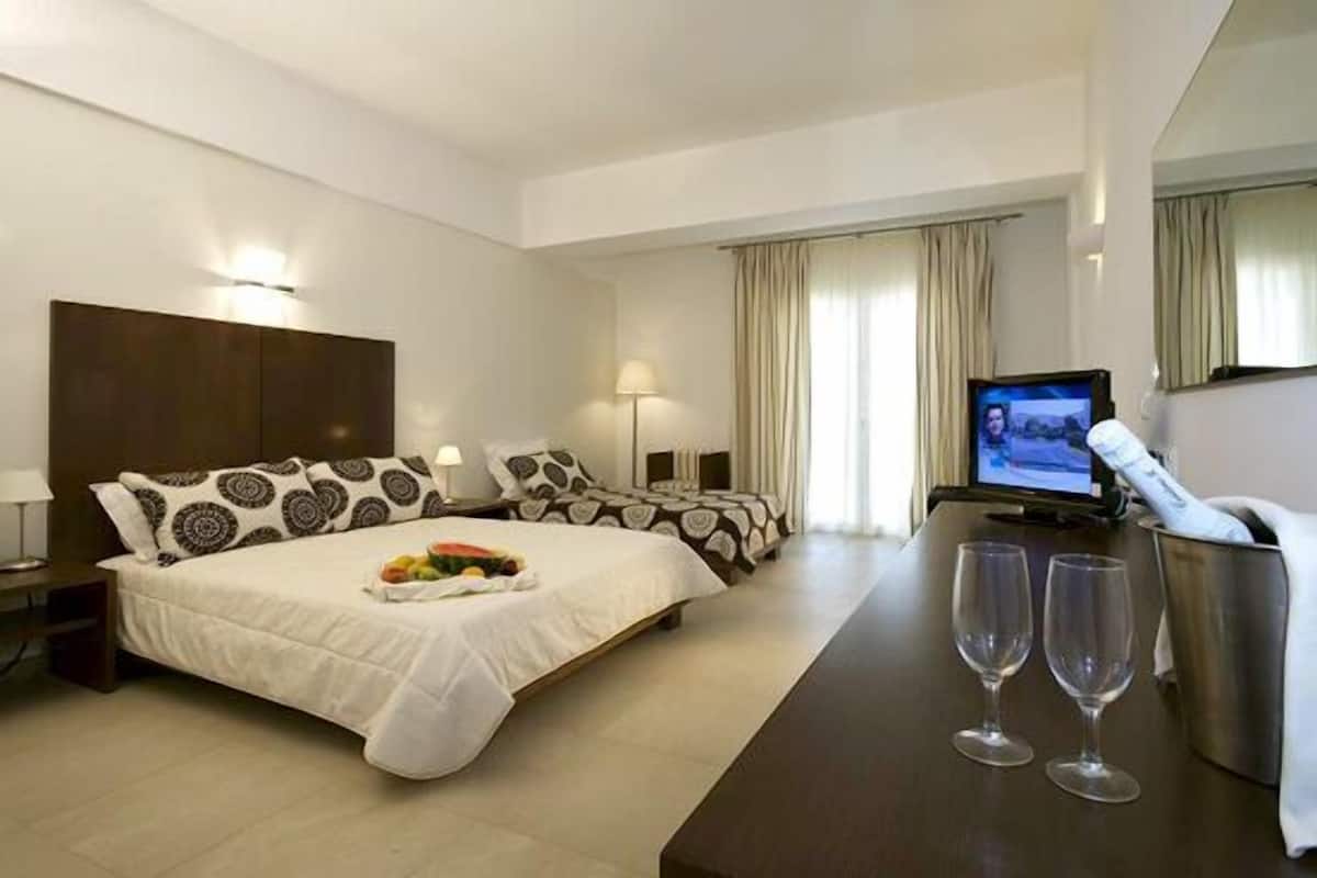Una habitación de hotel con una cama grande, una cama más pequeña, un televisor y un mini bar.