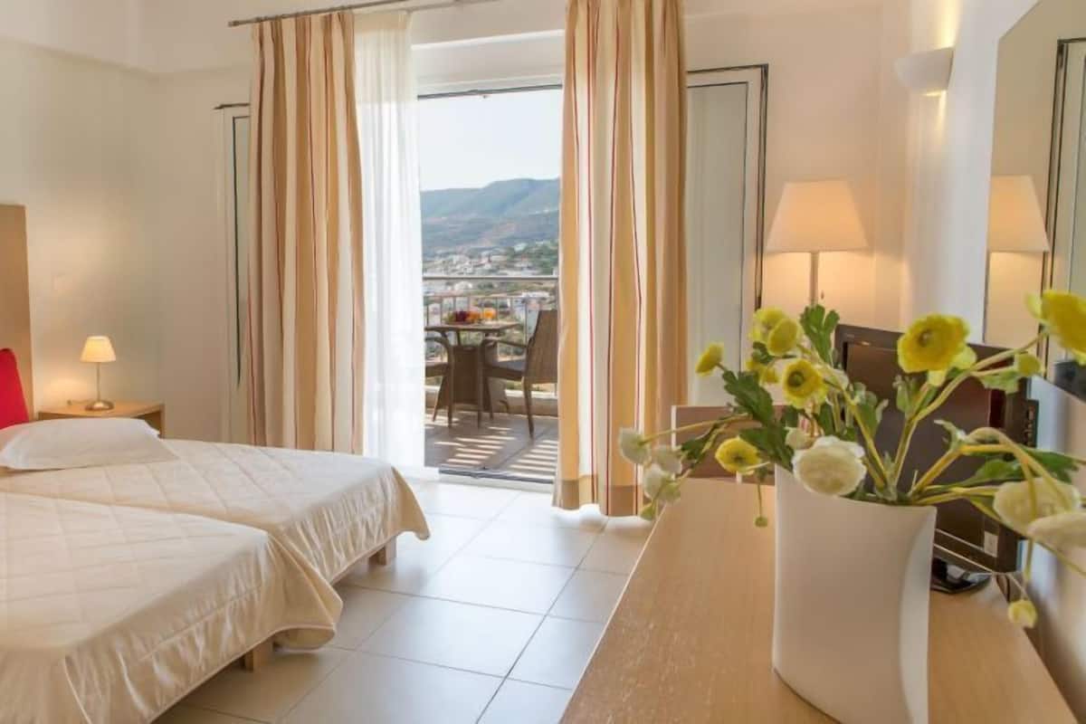 Habitación de hotel con dos camas, un escritorio y vistas a la ciudad.