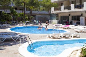 A pool area with multiple pools, lounge chairs, and tables.