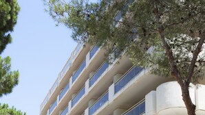 Un edificio de varios pisos con un diseño arquitectónico moderno, que presenta una entrada destacada con escalones que la conducen.