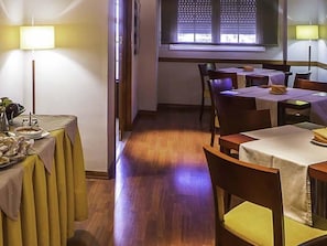 A hotel room with a dining area, a window with blinds, a lamp, and a table set for a meal. - Hotel Midama (Chillaron de Cuenca)