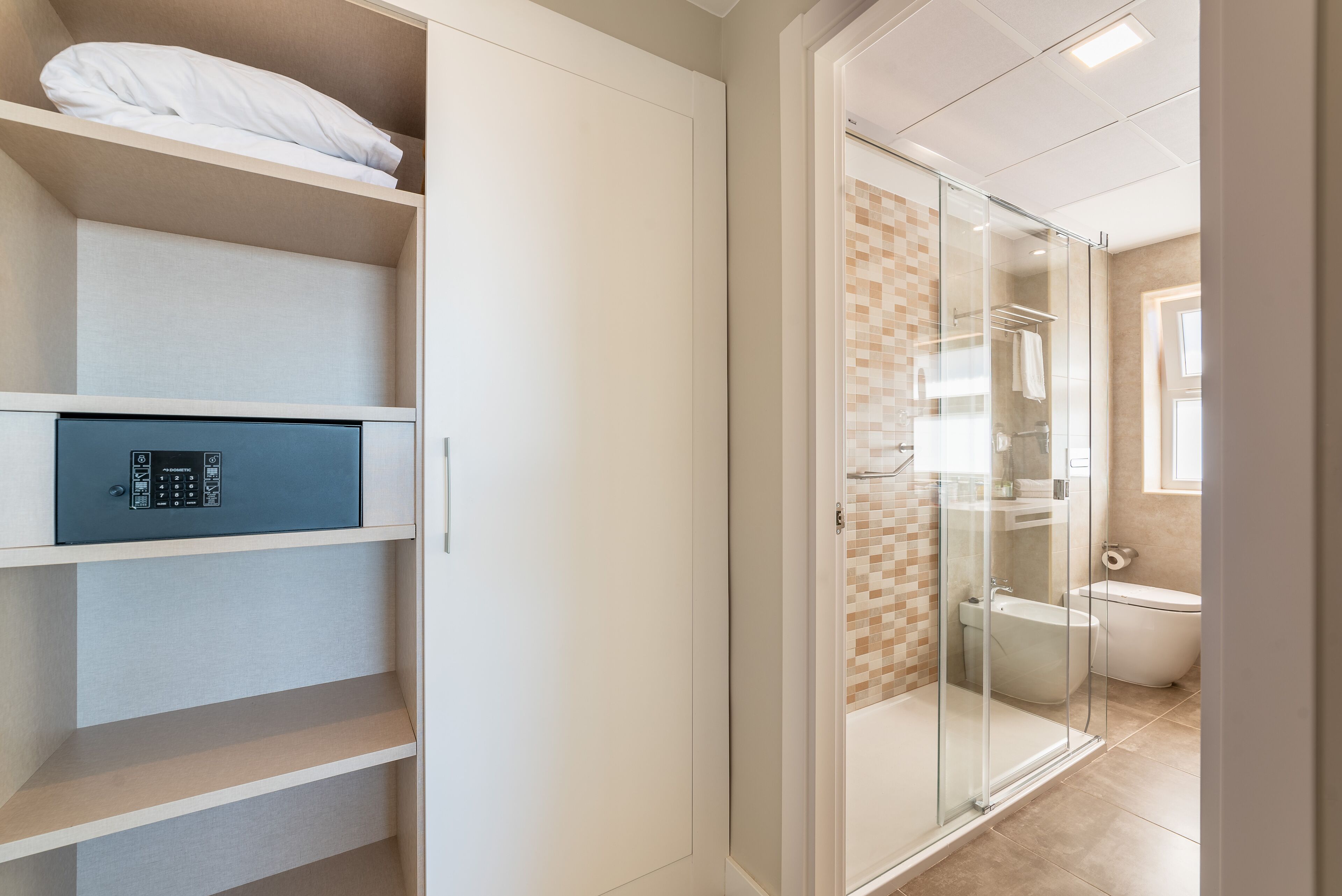 A modern bathroom with a glass shower enclosure, a toilet, and a built-in storage unit with a lock.