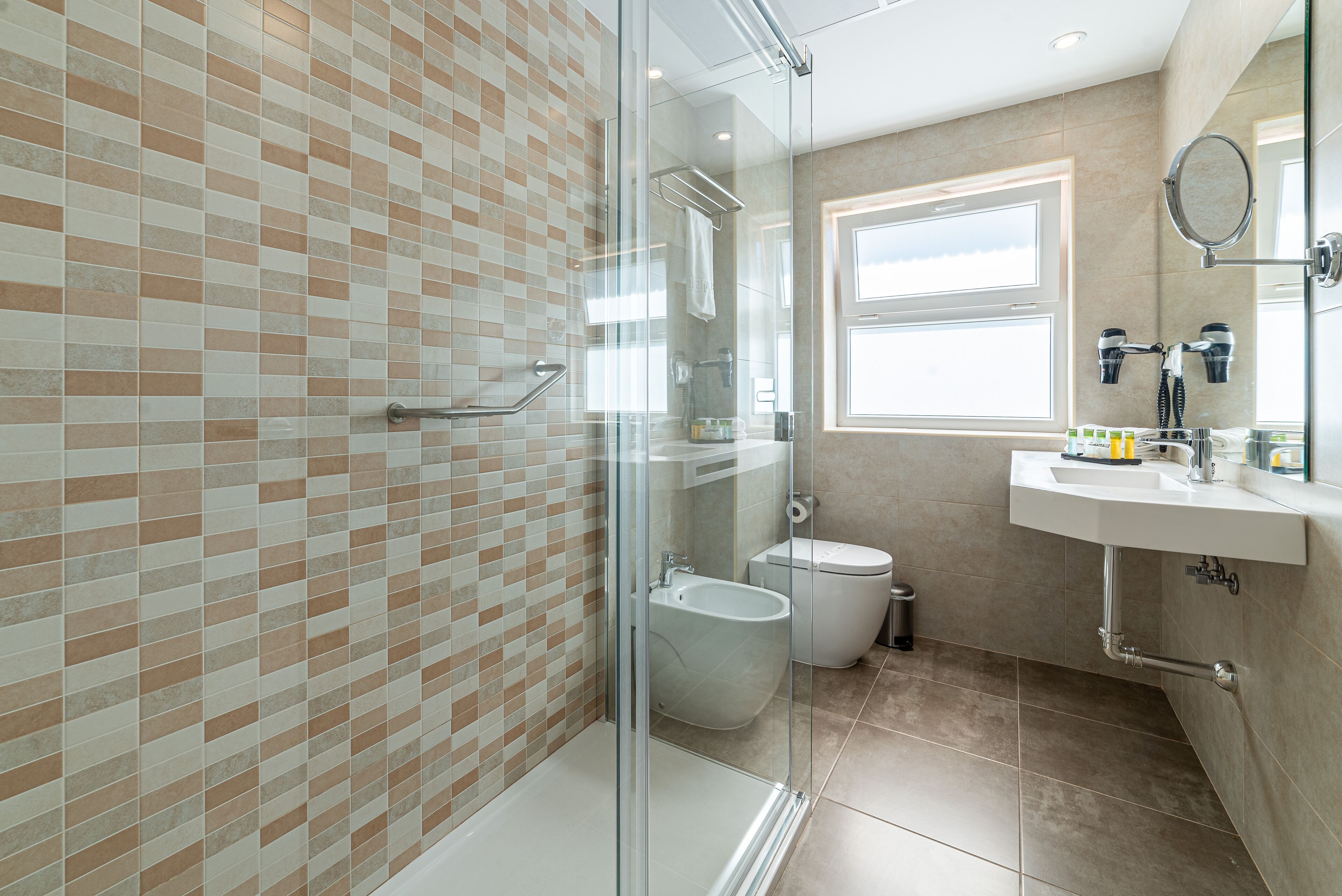 Un baño moderno con ducha de vidrio, inodoro blanco y lavamanos con espejo.