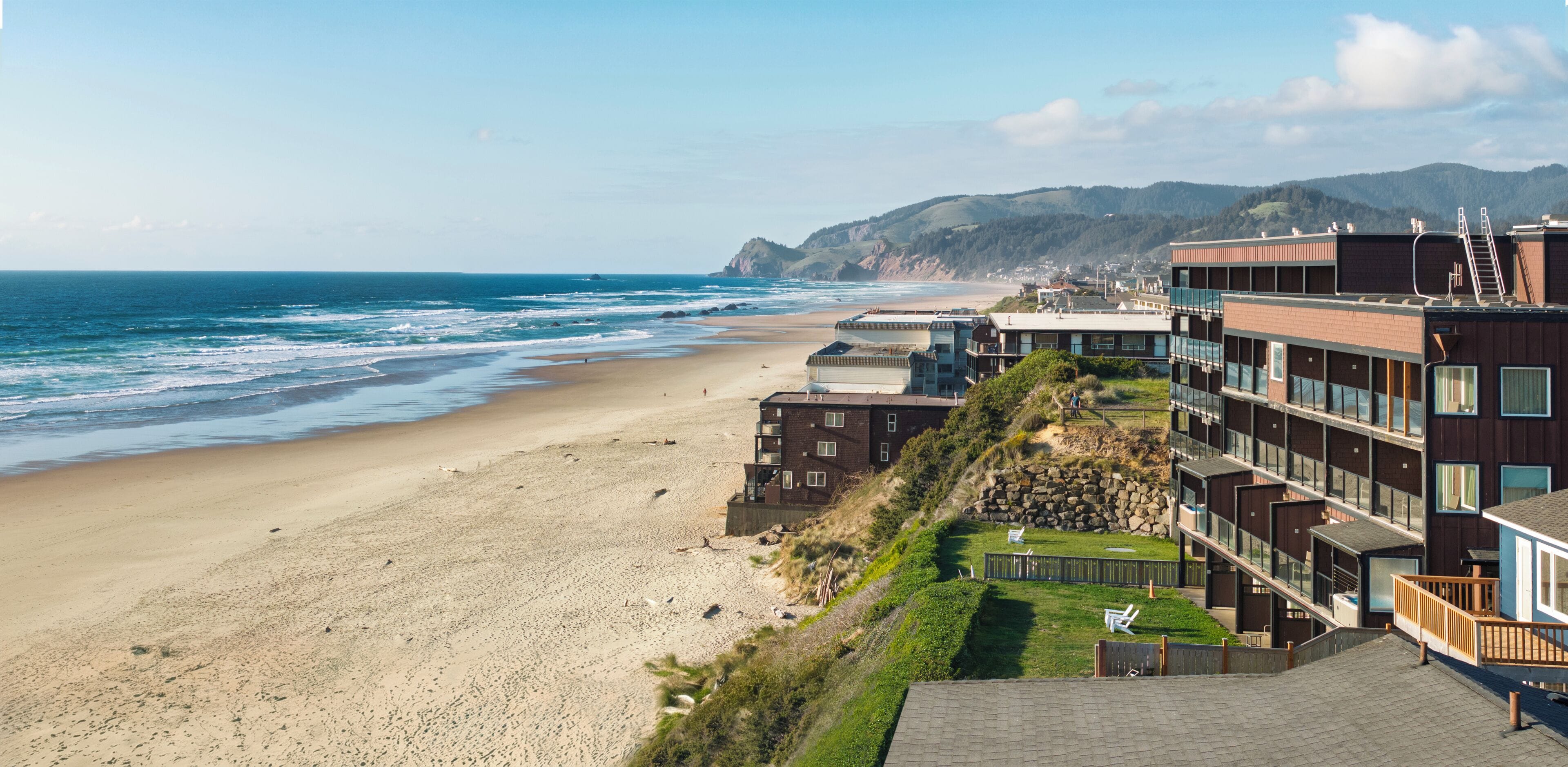 Un hotel sul lungomare con diversi piani, vista sulla spiaggia e un pendio roccioso.