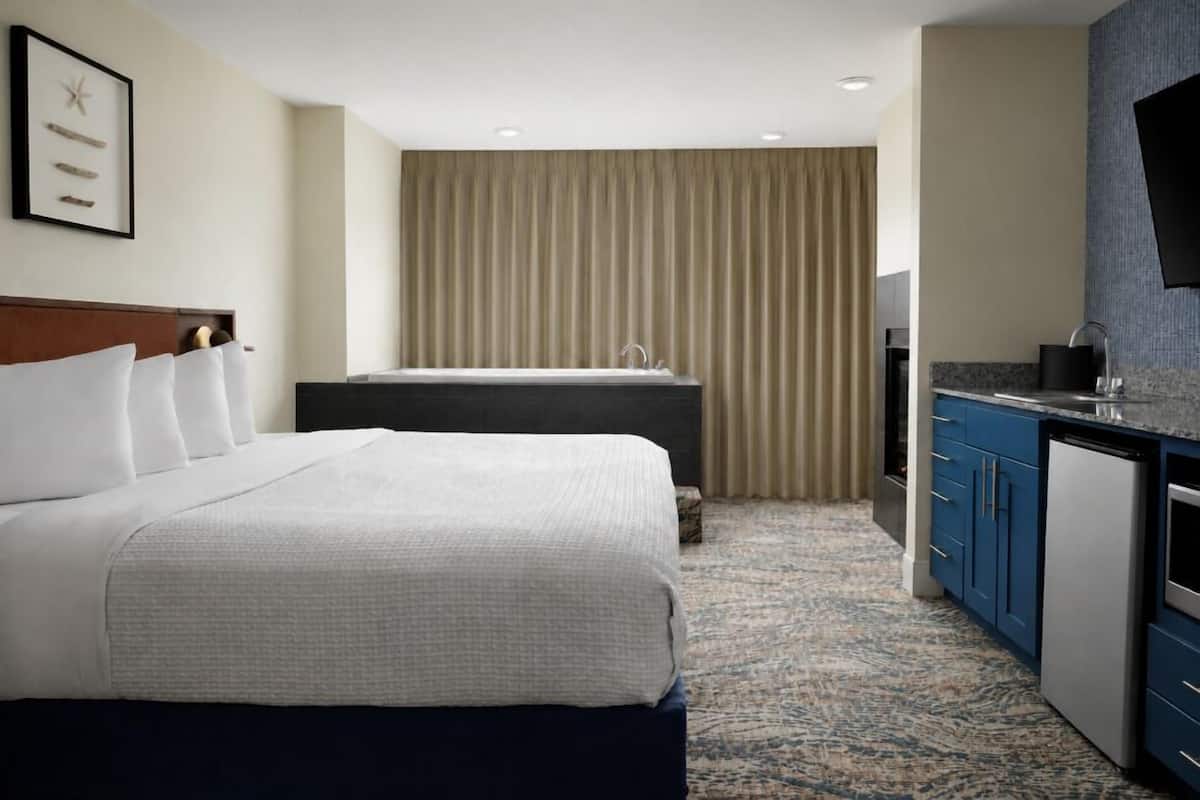 Ein Hotelzimmer mit Bett, Schreibtisch, Waschbecken und Fernseher.