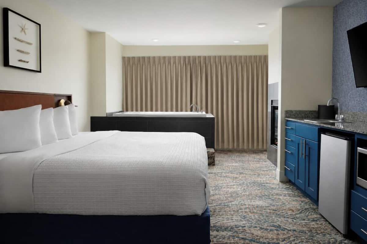 Ein Hotelzimmer mit Bett, Schreibtisch, Waschbecken und Fernseher.