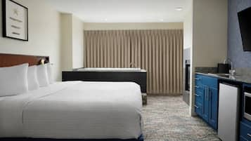 Una habitación de hotel con cama, un escritorio pequeño, un lavamanos y televisor.