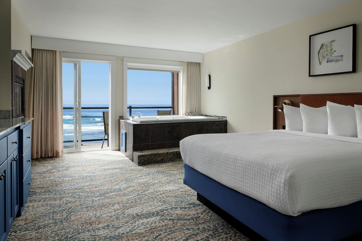Ein Hotelzimmer mit einem großen Bett, einer Badewanne und Meerblick.