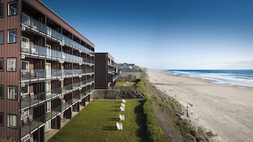 Een modern hotel met meerdere balkons met uitzicht op een strand.