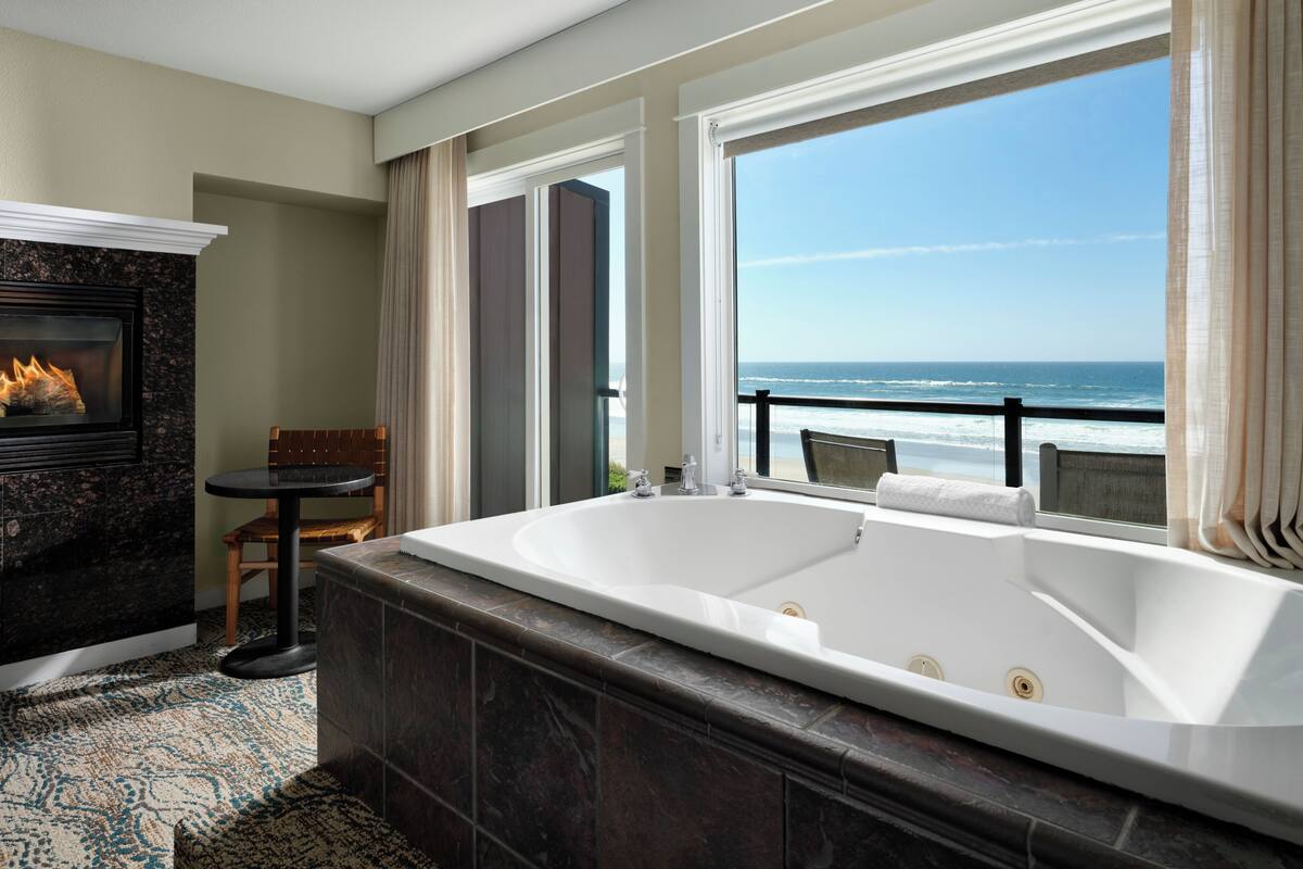Ein Badezimmer mit einer großen Badewanne, einem Kamin und Meerblick.