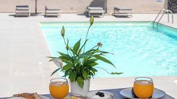 A table with breakfast items, a pool, and a view of the ocean.