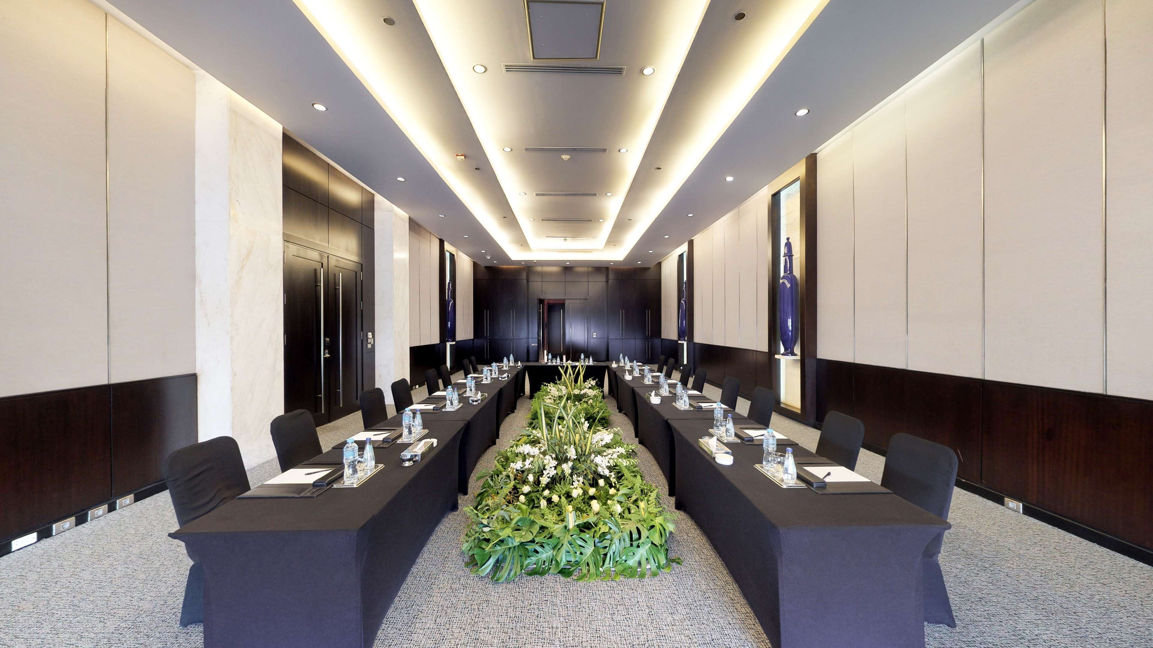 Una sala de conferencias moderna con una larga mesa, sillas y un centro de mesa floral.
