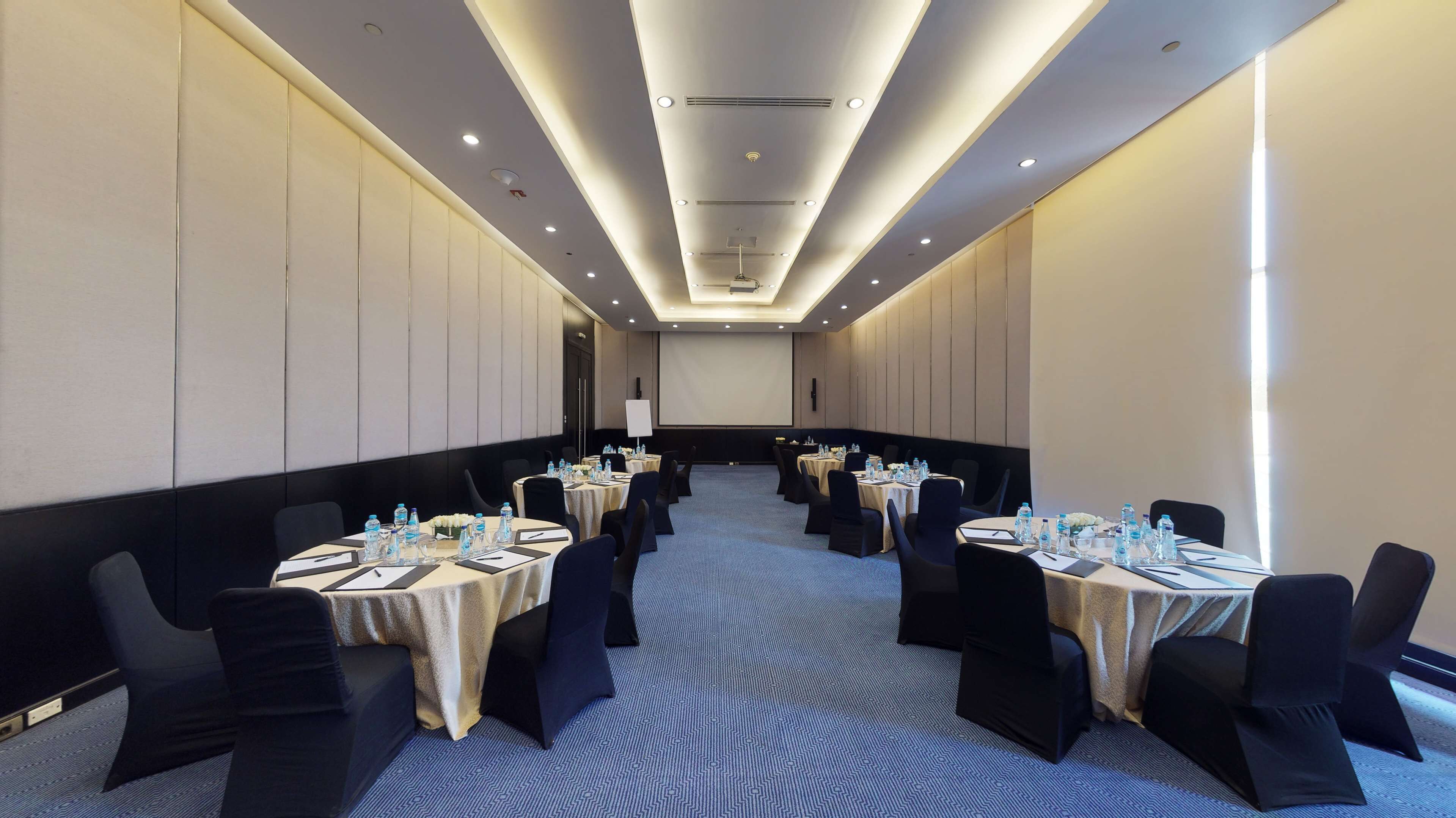 A conference room with round tables, black chairs, and water bottles.