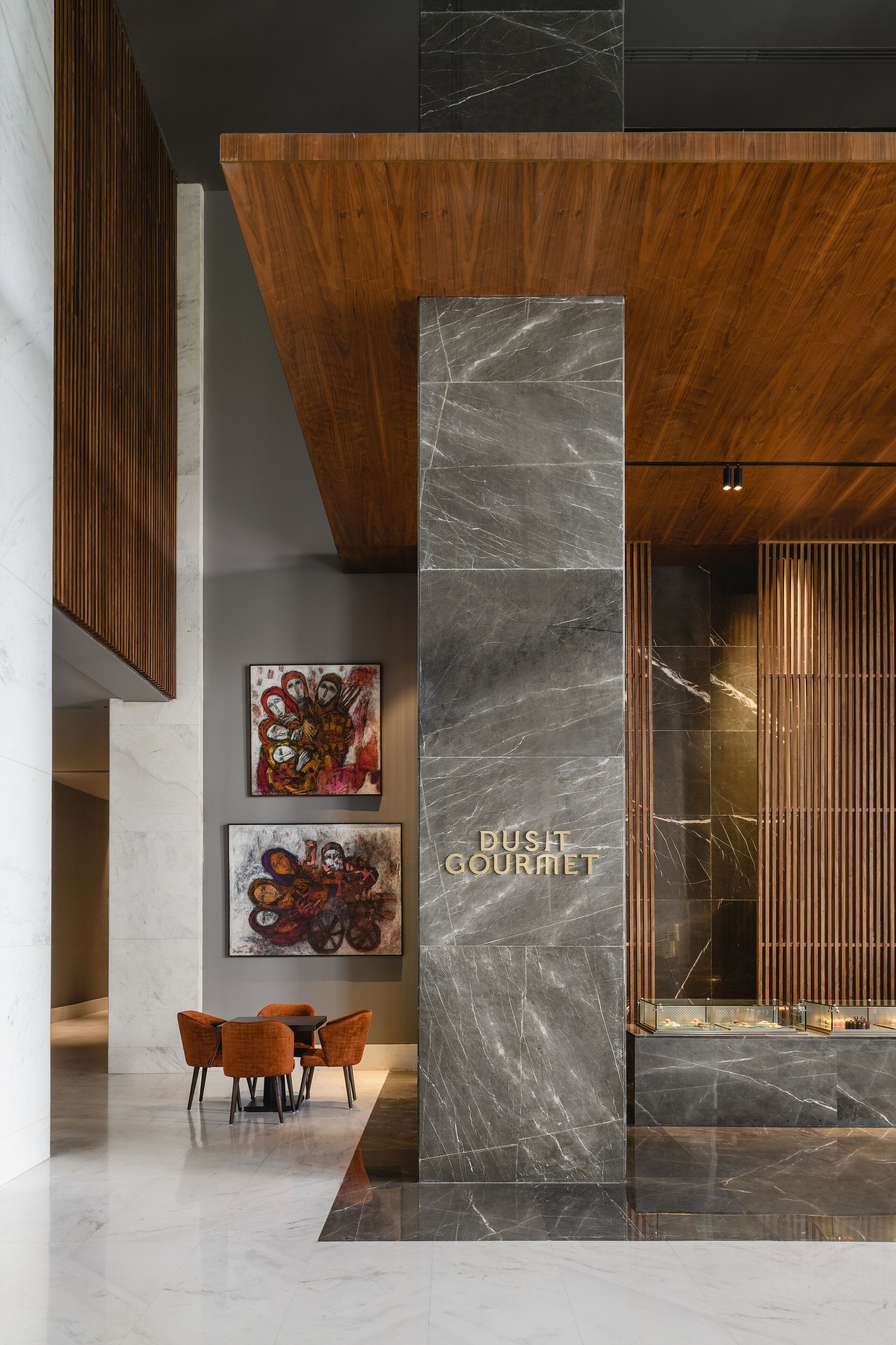A modern lobby with a wooden reception desk, marble walls, and contemporary artwork.