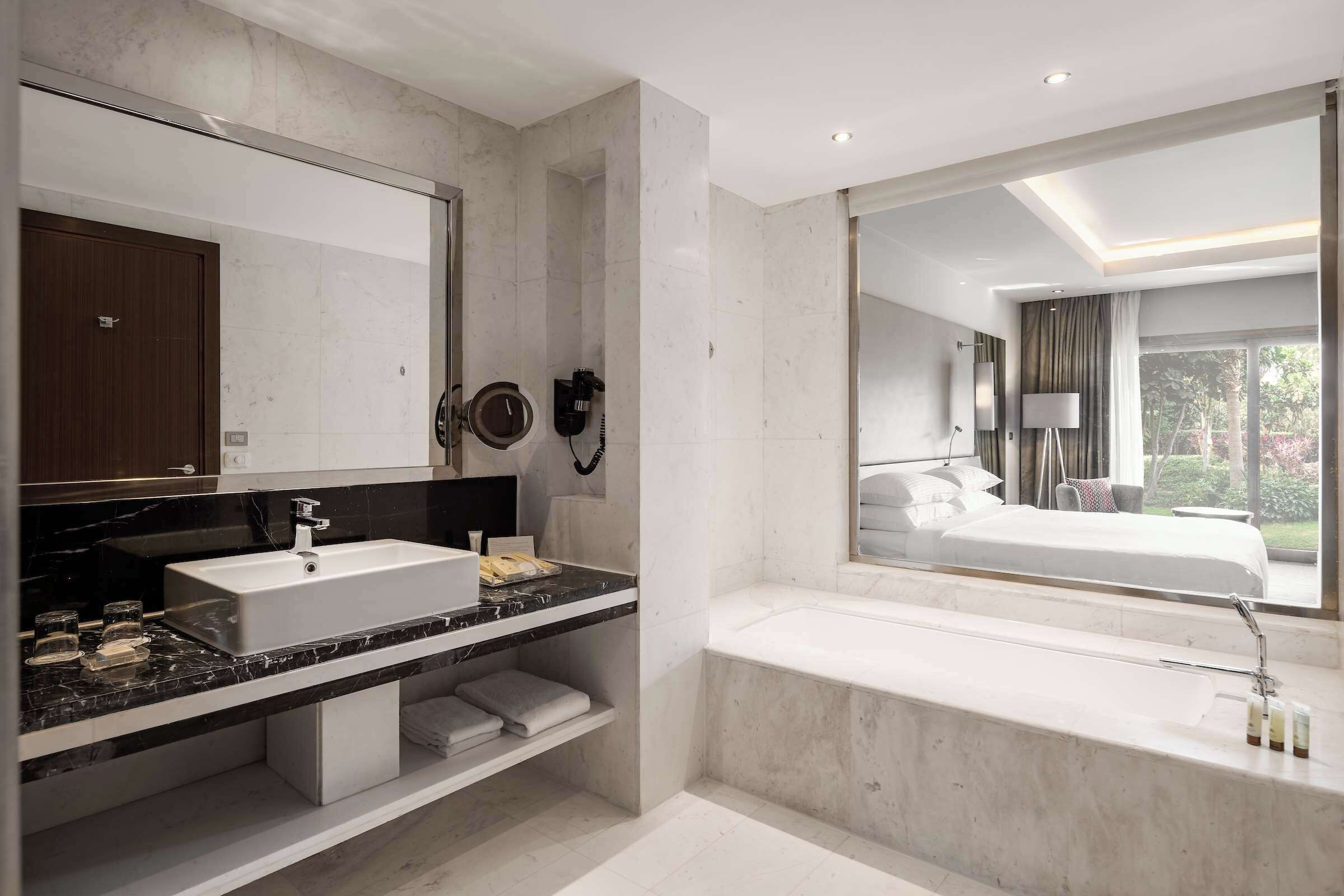 Un baño moderno con un espejo grande, un lavabo blanco, una bañera y una ducha.