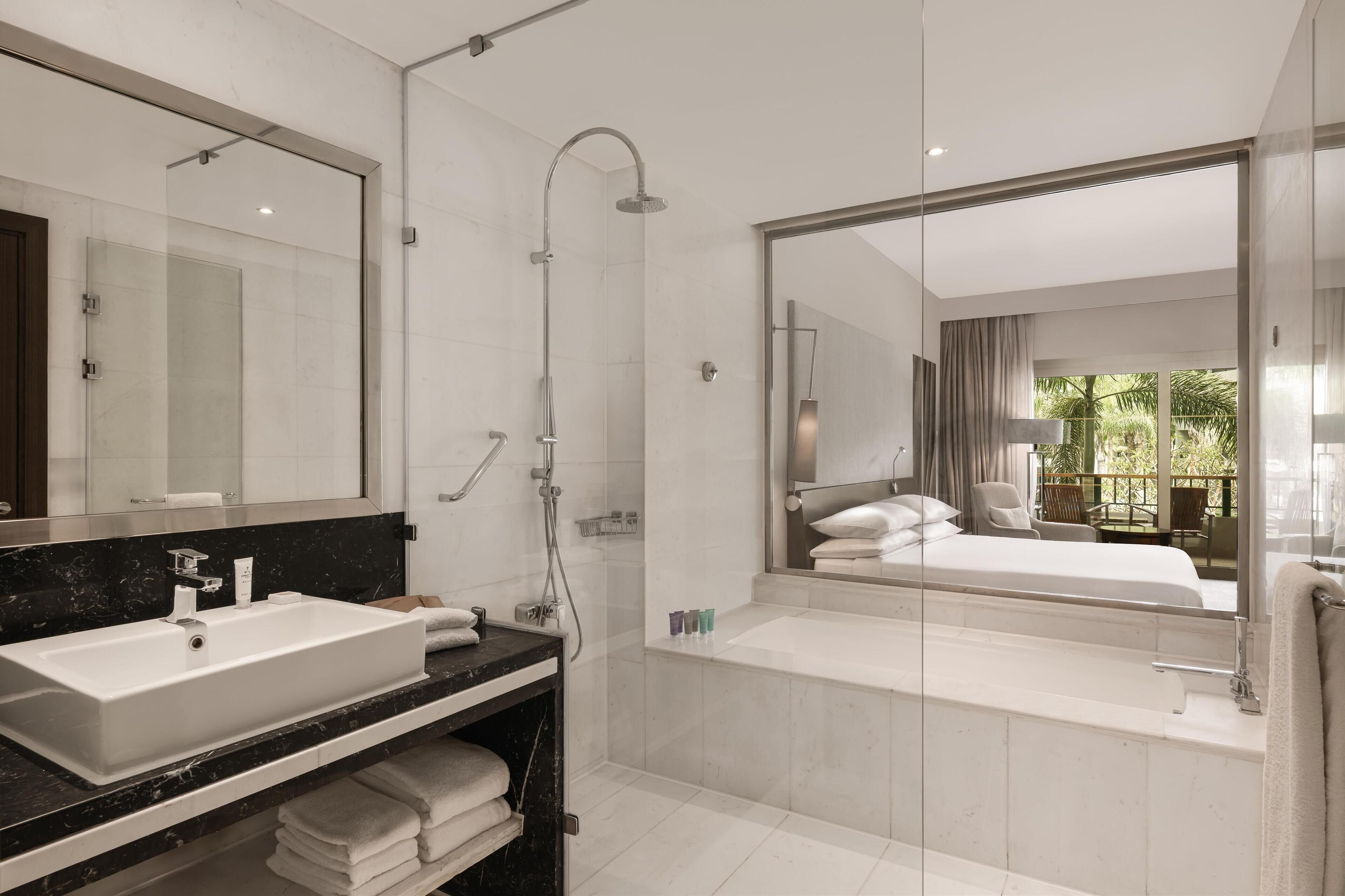 Een moderne badkamer met een grote spiegel, een wastafel, een douche en een bad.