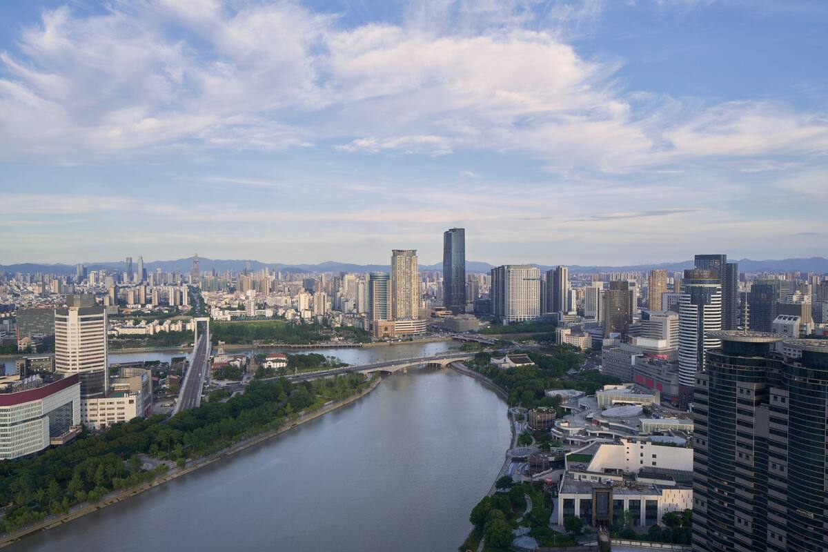 A cityscape with a river, modern buildings, and a bridge.