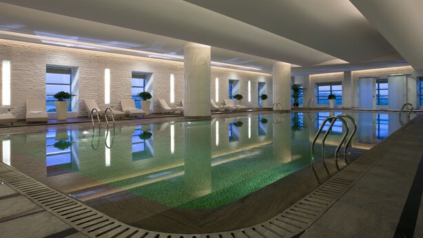 A large indoor swimming pool with clear water, surrounded by lounge chairs and potted plants. - Ningbo Marriott Hotel (Ningbo)