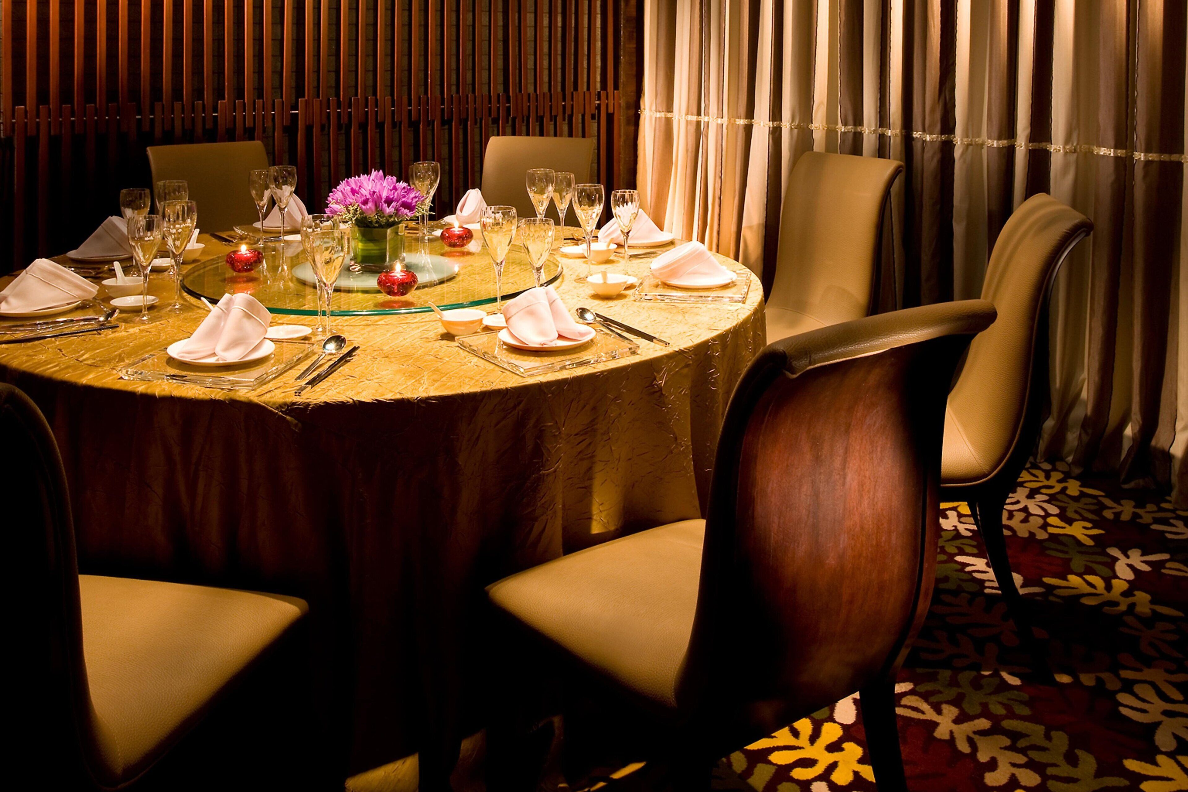A round dining table set for a meal with chairs around it.