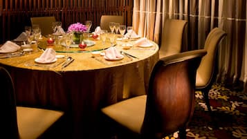 A round dining table set for a meal with chairs around it.