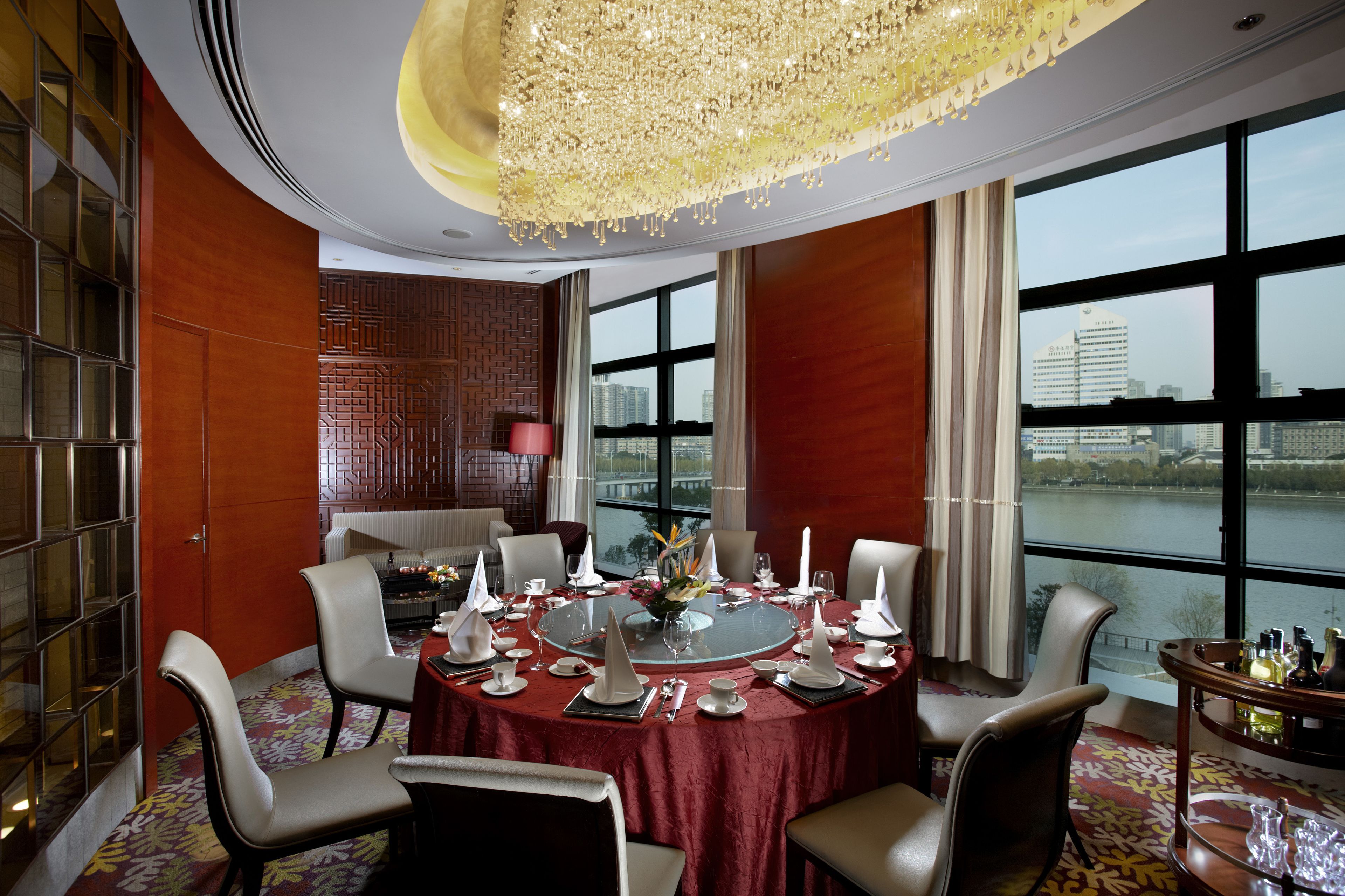 A dining room with a round table set for six, large windows, and a view of a river.