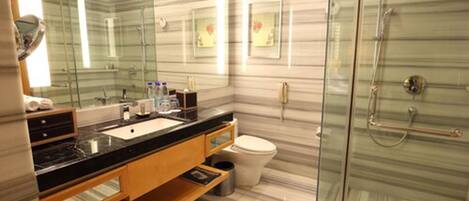 A modern bathroom with a glass shower enclosure, a marble vanity, and a large mirror.