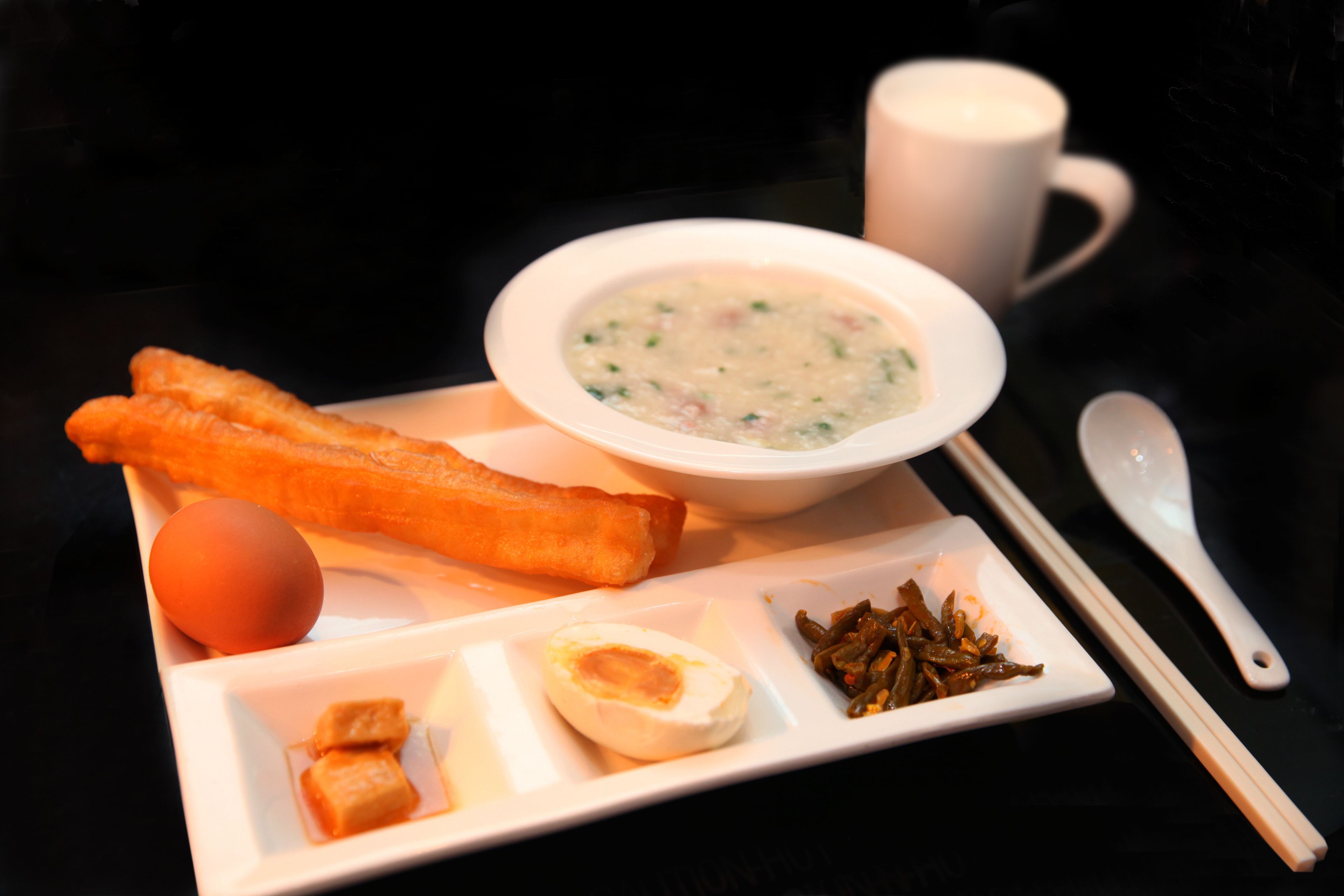 A tray with a bowl of soup, two fried items, a boiled egg, and some pickled vegetables.