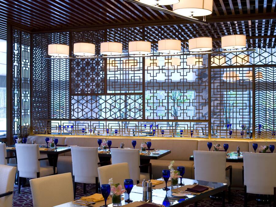 Ein Restaurant mit mehreren Tischen, Stühlen und hängenden Lampen.