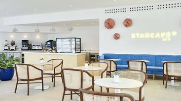 Un café moderno con mobiliario de mimbre, una barra de café y un letrero de neón que dice 'STARCAFE'.