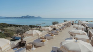 A rooftop terrace with multiple sun loungers and umbrellas, overlooking a coastal landscape with mountains and a pier. - Iberostar Selection Albufera Park - All Inclusive (Muro)