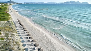 A beach with a long stretch of umbrellas and a pier extending into the water. - Iberostar Selection Albufera Park - All Inclusive (Muro)