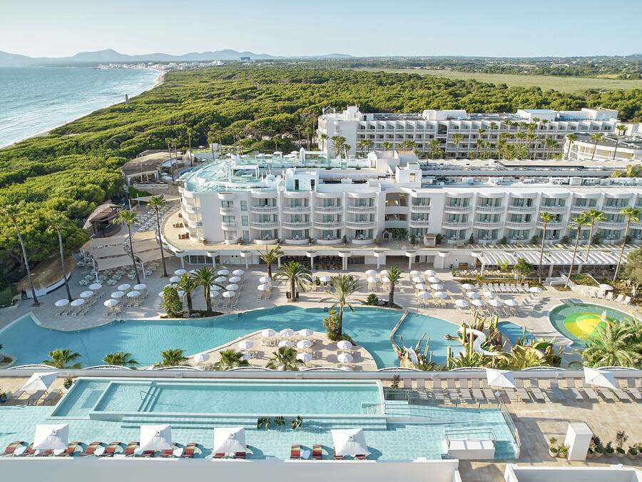 A resort with multiple swimming pools, a beach, and lush greenery.